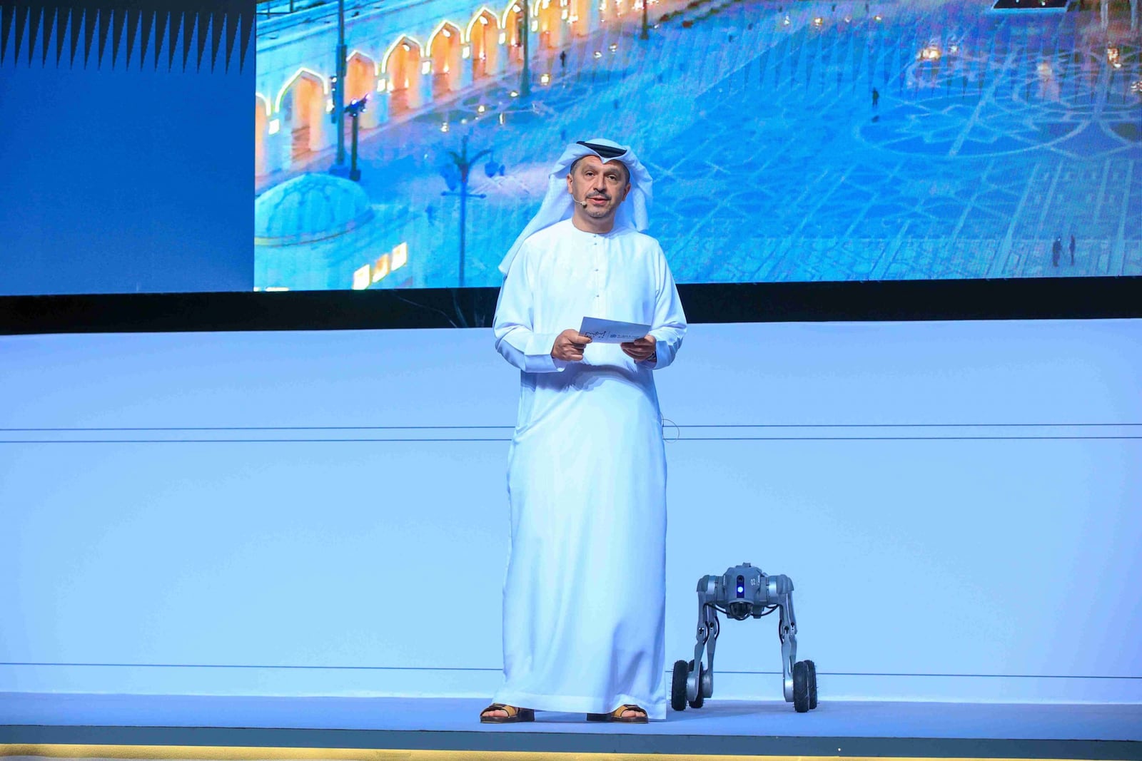 A speaker and a quadruped robot on stage at the IROS 2024 opening in Abu Dhabi